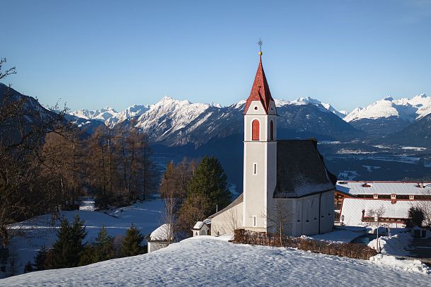 Mösern im Winter Drohnenaufnahme Pfarrkirche Maria Heimsuchung Nahaufnahme vor Inntal
